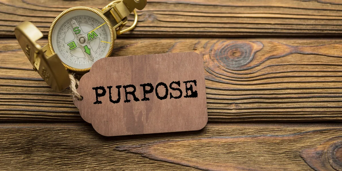 A wooden tag with the word 'PURPOSE' on a rustic wooden surface.